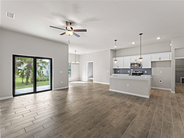 kitchen featuring white cabinets, visible vents, stainless steel microwave, and open floor plan