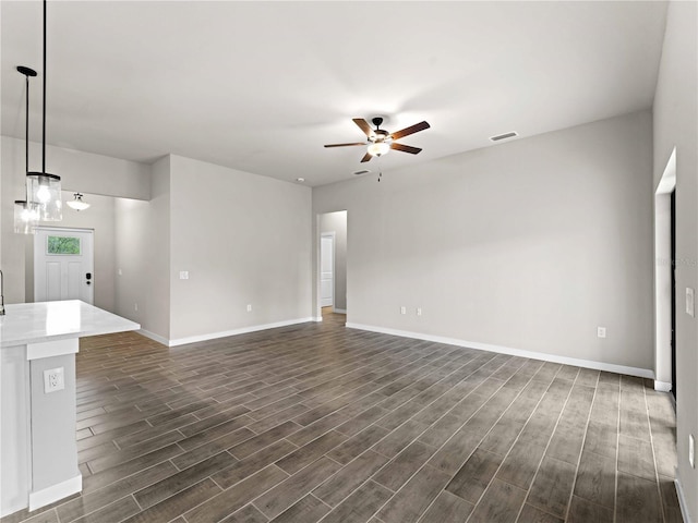 unfurnished living room featuring a ceiling fan, baseboards, visible vents, and dark wood-type flooring