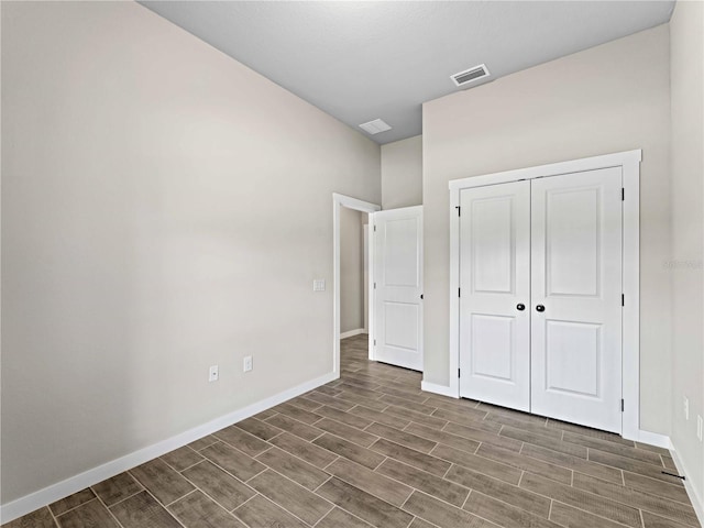 unfurnished bedroom with wood tiled floor, a closet, visible vents, and baseboards