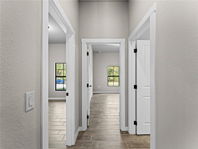 hall with wood tiled floor, baseboards, and a textured wall