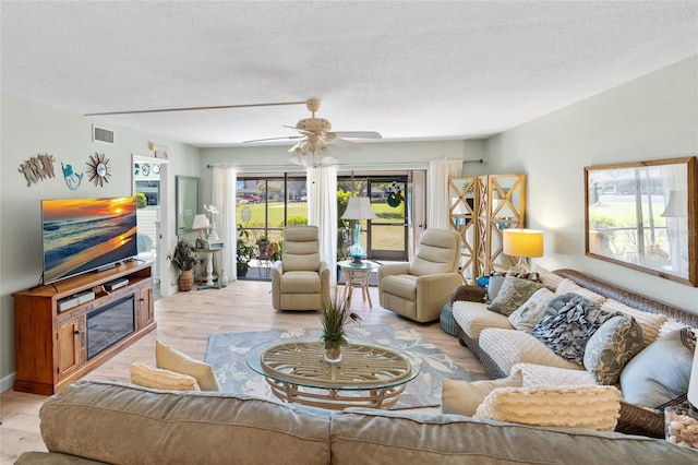 living room with visible vents, ceiling fan, a textured ceiling, and light wood-style floors