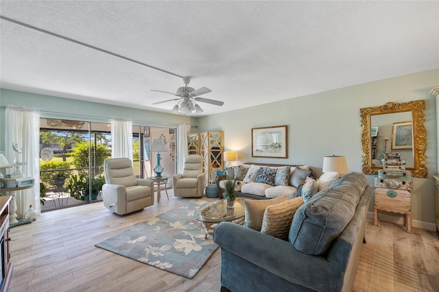 living room featuring light wood-style floors, ceiling fan, and a textured ceiling