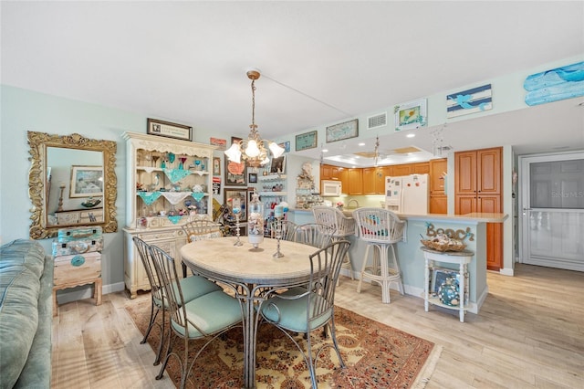 dining space with a notable chandelier, visible vents, baseboards, and light wood-style floors