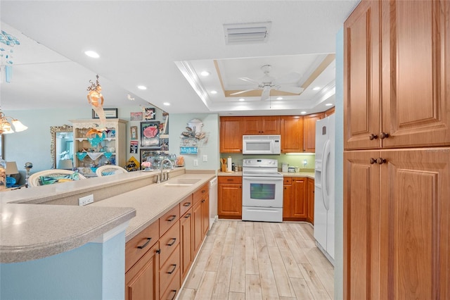 kitchen with light wood-style flooring, a sink, recessed lighting, white appliances, and a raised ceiling