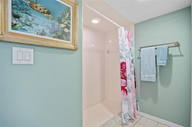 full bath with tile patterned floors, baseboards, and a tile shower