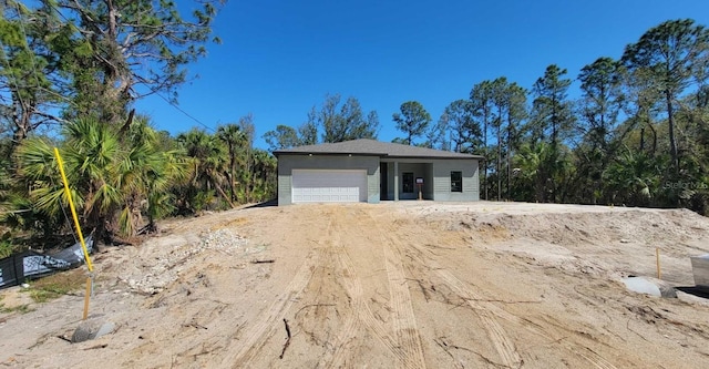 view of front facade with a garage and dirt driveway