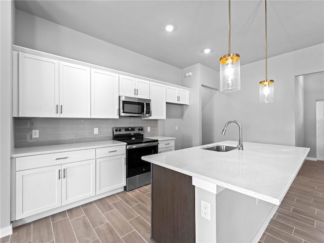 kitchen with wood finish floors, decorative backsplash, appliances with stainless steel finishes, white cabinets, and a sink