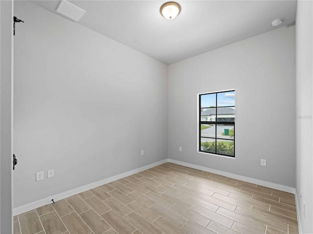 unfurnished room featuring wood tiled floor, visible vents, and baseboards