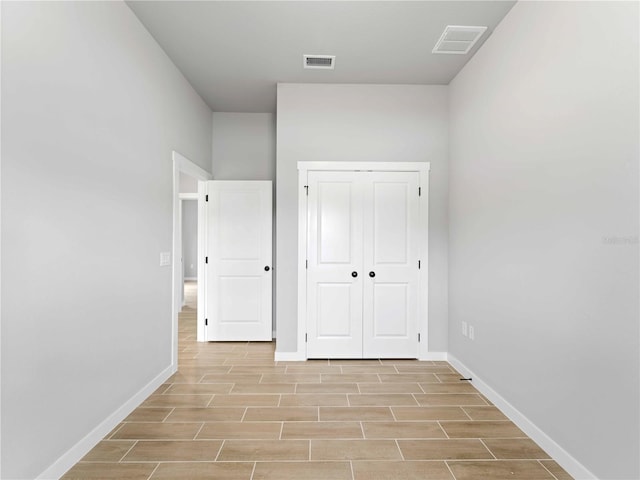 unfurnished bedroom with wood tiled floor, a closet, visible vents, and baseboards