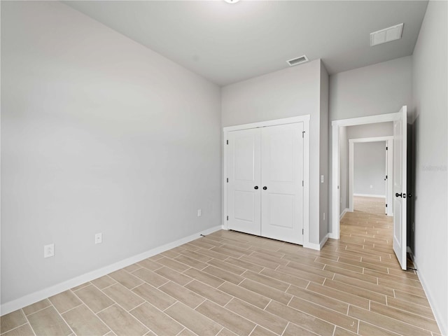 unfurnished bedroom featuring a closet, baseboards, visible vents, and light wood finished floors