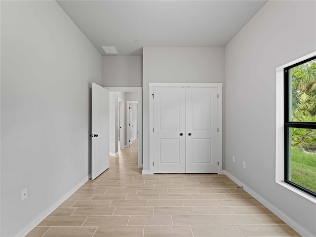 unfurnished bedroom featuring wood tiled floor, multiple windows, and baseboards