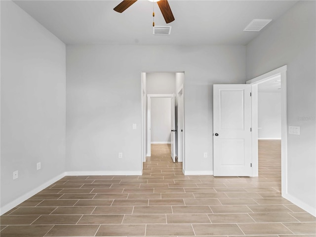 unfurnished bedroom with a ceiling fan, wood tiled floor, visible vents, and baseboards