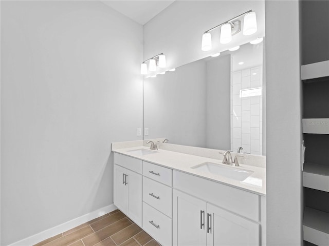 bathroom featuring double vanity, baseboards, a sink, and wood finish floors