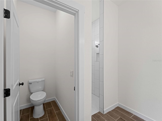 12156 Wellington Ave, Port Charlotte, FL 33981 - bathroom featuring wood finish floors, toilet, a tile shower, and baseboards