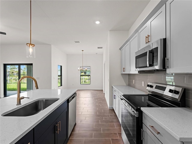 12156 Wellington Ave, Port Charlotte, FL 33981 - kitchen with stainless steel appliances, a sink, decorative backsplash, decorative light fixtures, and light stone countertops