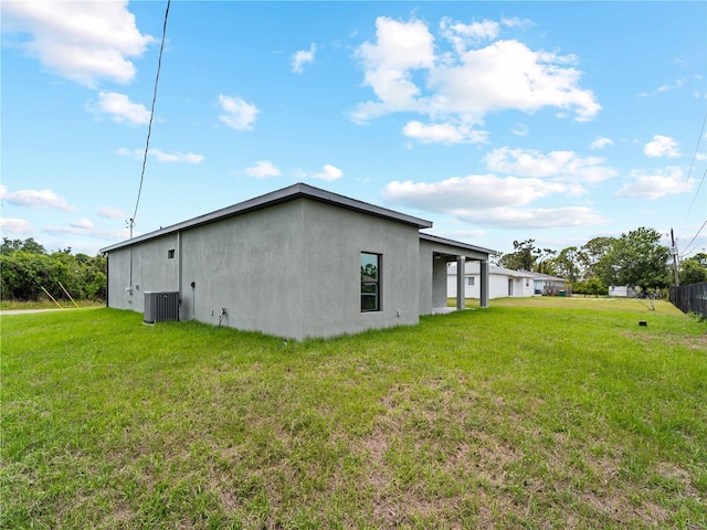 12156 Wellington Ave, Port Charlotte, FL 33981 - view of side of home with stucco siding, central AC unit, and a yard