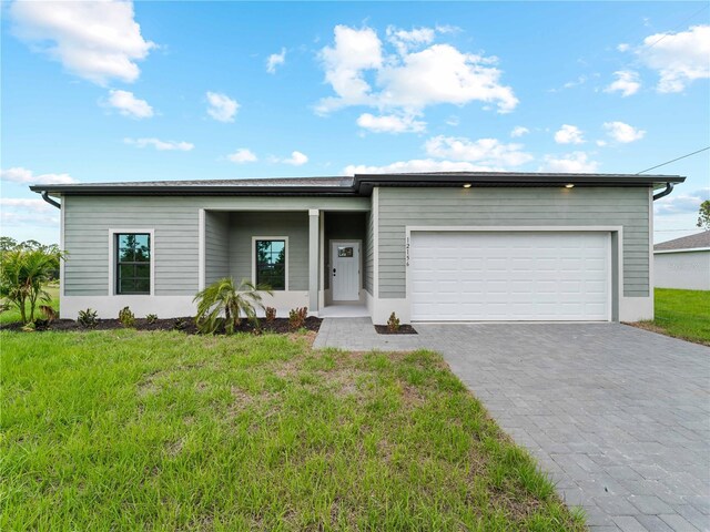 12156 Wellington Ave, Port Charlotte, FL 33981 - view of front facade with decorative driveway, an attached garage, and a front lawn