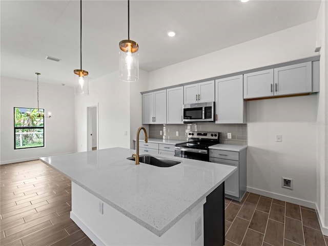 12156 Wellington Ave, Port Charlotte, FL 33981 - kitchen with stainless steel appliances, a sink, wood finish floors, backsplash, and light stone countertops