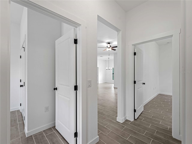 corridor featuring wood tiled floor and baseboards