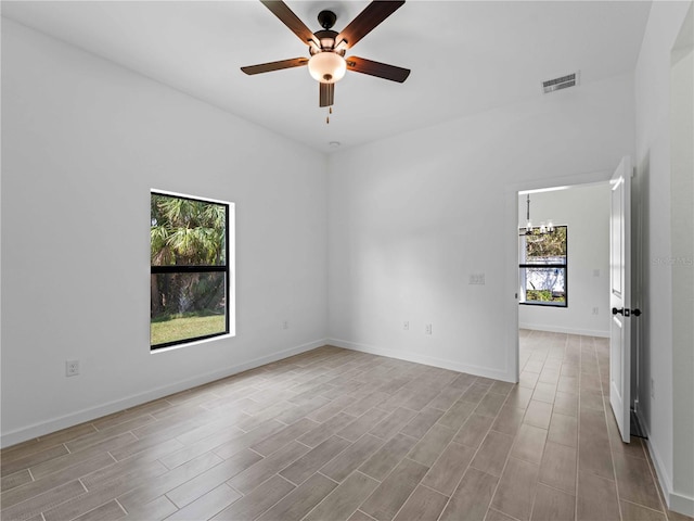 empty room featuring baseboards, visible vents, wood finished floors, and ceiling fan with notable chandelier