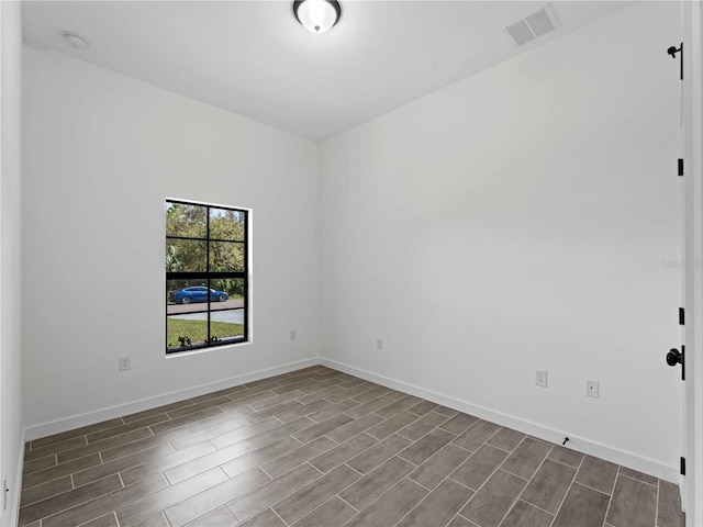 unfurnished room featuring baseboards, visible vents, and wood finish floors