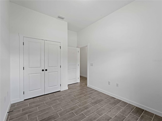 unfurnished bedroom featuring baseboards, wood tiled floor, visible vents, and a closet