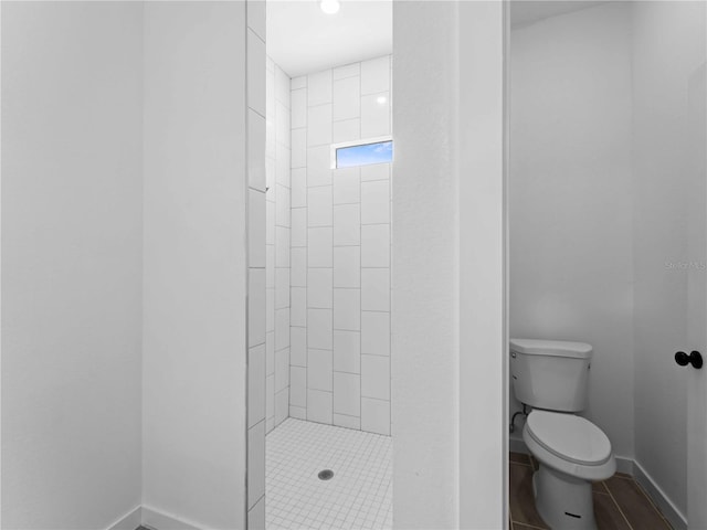 bathroom with baseboards, a shower stall, and toilet