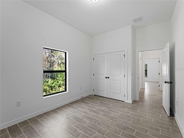 unfurnished bedroom with a closet, wood finished floors, visible vents, and baseboards