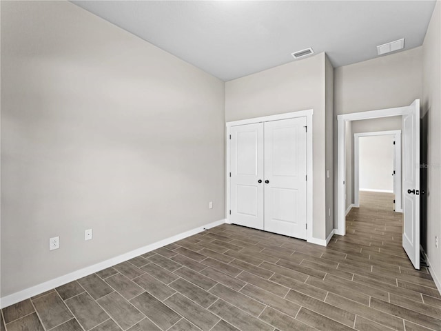 unfurnished bedroom featuring wood tiled floor, a closet, visible vents, and baseboards