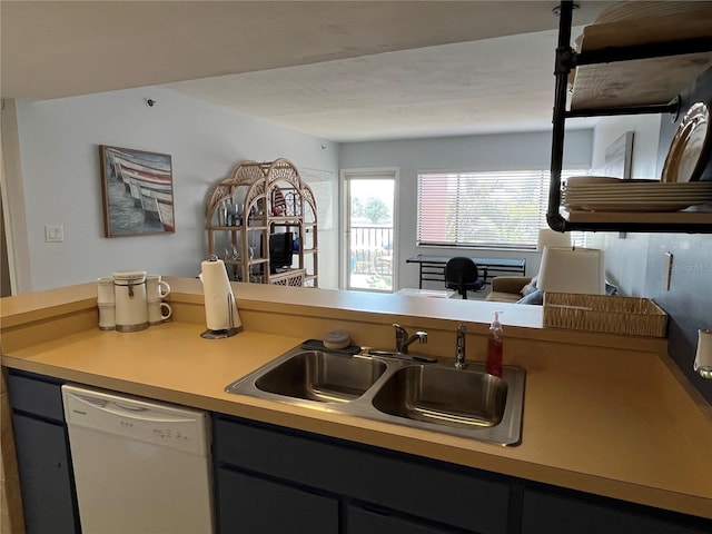 kitchen with light countertops, white dishwasher, and a sink