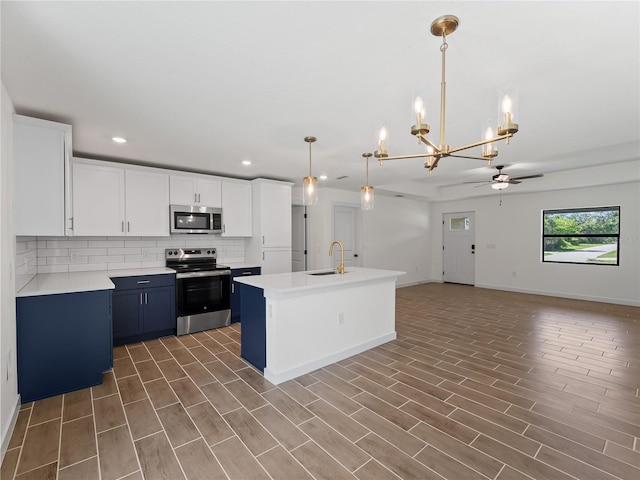 17331 Elmwood Ave, Port Charlotte, FL 33948 - kitchen featuring stainless steel appliances, ceiling fan, blue cabinets, a chandelier, and tasteful backsplash
