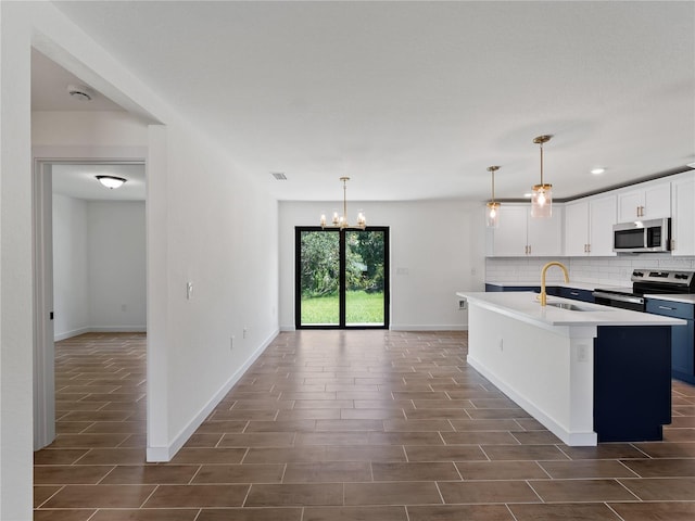 17331 Elmwood Ave, Port Charlotte, FL 33948 - kitchen with appliances with stainless steel finishes, wood tiled floors, decorative backsplash, a center island with sink, and a chandelier