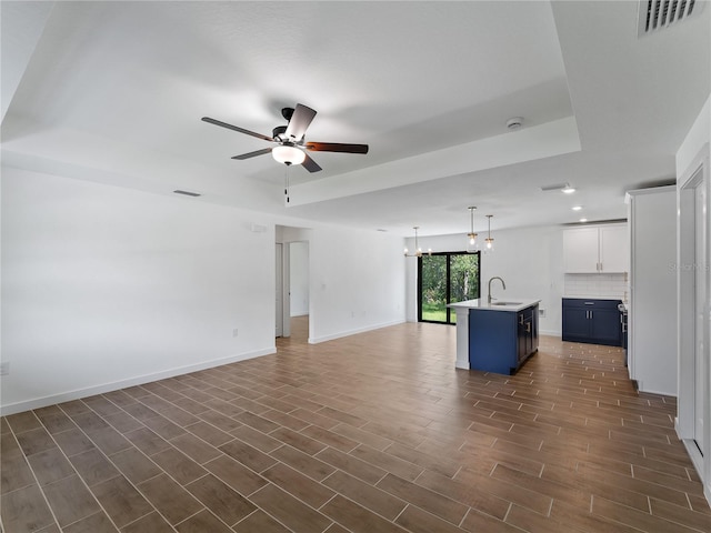 17331 Elmwood Ave, Port Charlotte, FL 33948 - unfurnished living room featuring a ceiling fan, a tray ceiling, dark wood finished floors, and a chandelier