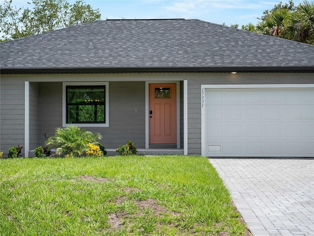 17331 Elmwood Ave, Port Charlotte, FL 33948 - ranch-style house featuring a shingled roof, a front yard, decorative driveway, and a garage