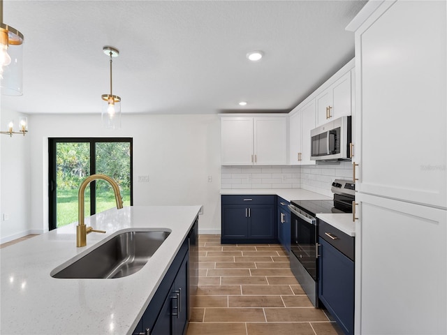 17331 Elmwood Ave, Port Charlotte, FL 33948 - kitchen with stainless steel appliances, blue cabinetry, decorative backsplash, white cabinets, and pendant lighting