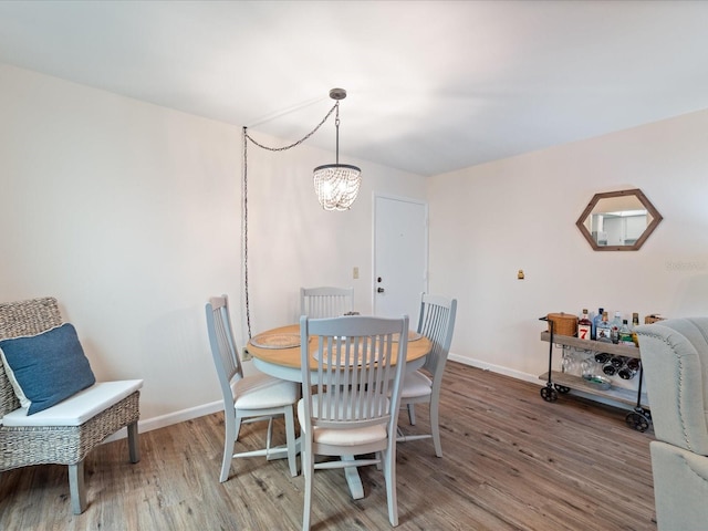 dining area featuring baseboards, a notable chandelier, and wood finished floors