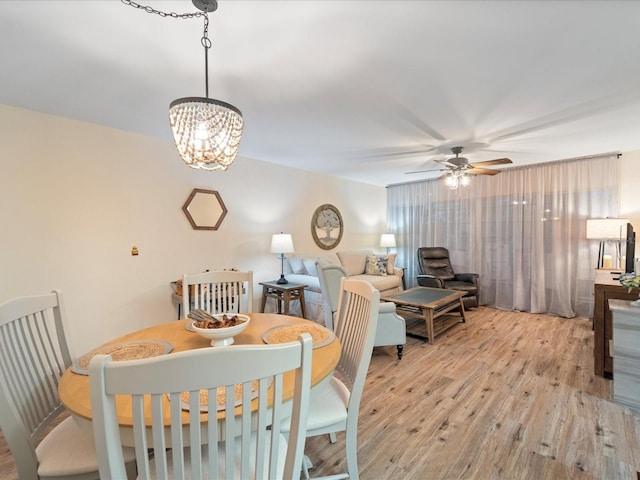 dining area with ceiling fan with notable chandelier and light wood-style floors