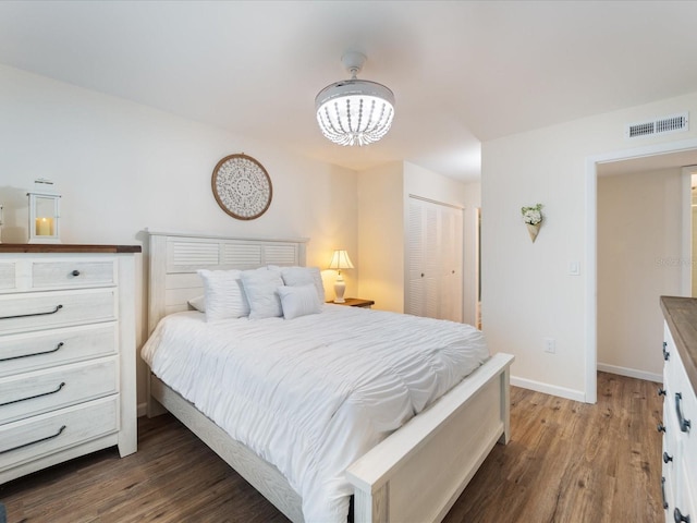 bedroom featuring visible vents, baseboards, an inviting chandelier, wood finished floors, and a closet