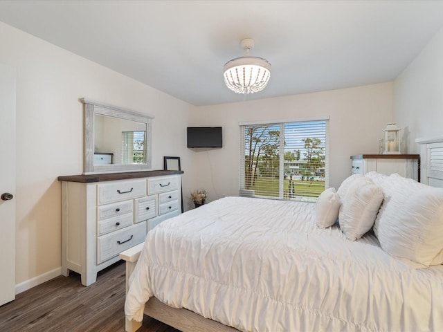 bedroom featuring an inviting chandelier, baseboards, and dark wood-type flooring