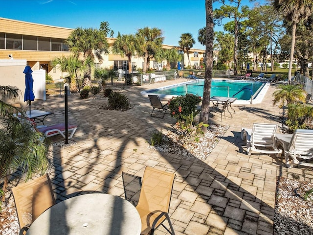 community pool with a patio and fence