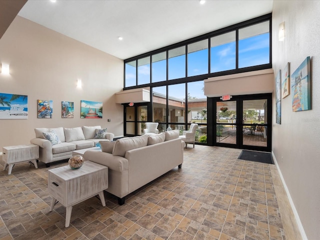 living area featuring a high ceiling, stone finish floor, recessed lighting, and baseboards