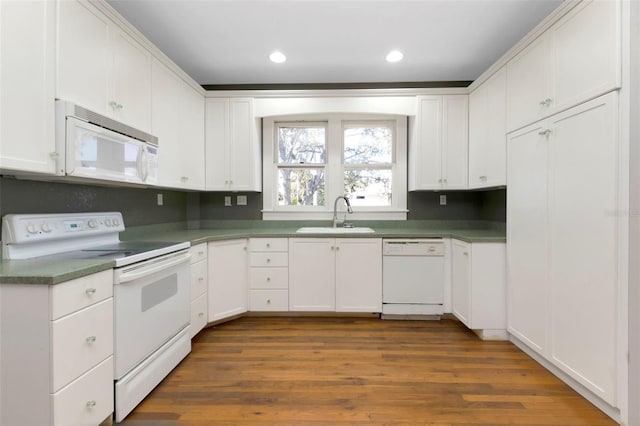 kitchen with recessed lighting, white appliances, a sink, white cabinetry, and dark wood finished floors