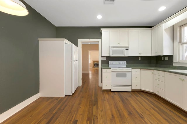 kitchen with white appliances, white cabinets, visible vents, and dark wood-style flooring