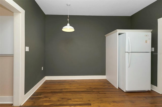 unfurnished dining area featuring baseboards and wood finished floors