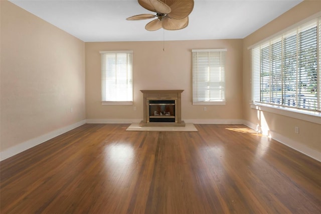 unfurnished living room with ceiling fan, baseboards, wood finished floors, and a glass covered fireplace