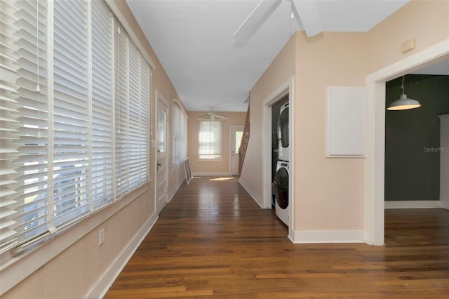 hall with baseboards, wood finished floors, and stacked washer and clothes dryer