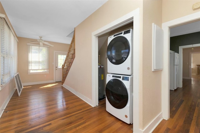 laundry area featuring laundry area, baseboards, dark wood finished floors, stacked washer / dryer, and electric water heater