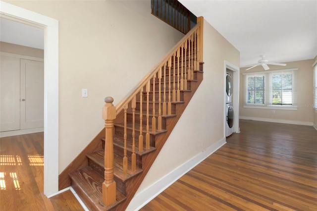 stairs featuring a ceiling fan, baseboards, wood finished floors, and stacked washer and clothes dryer