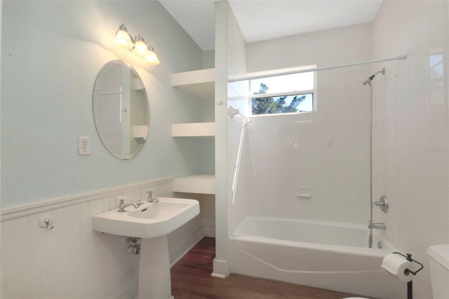 full bath with bathtub / shower combination, wainscoting, wood finished floors, and toilet