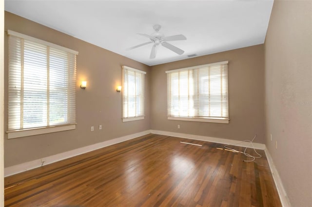 unfurnished room with ceiling fan, visible vents, baseboards, and wood finished floors